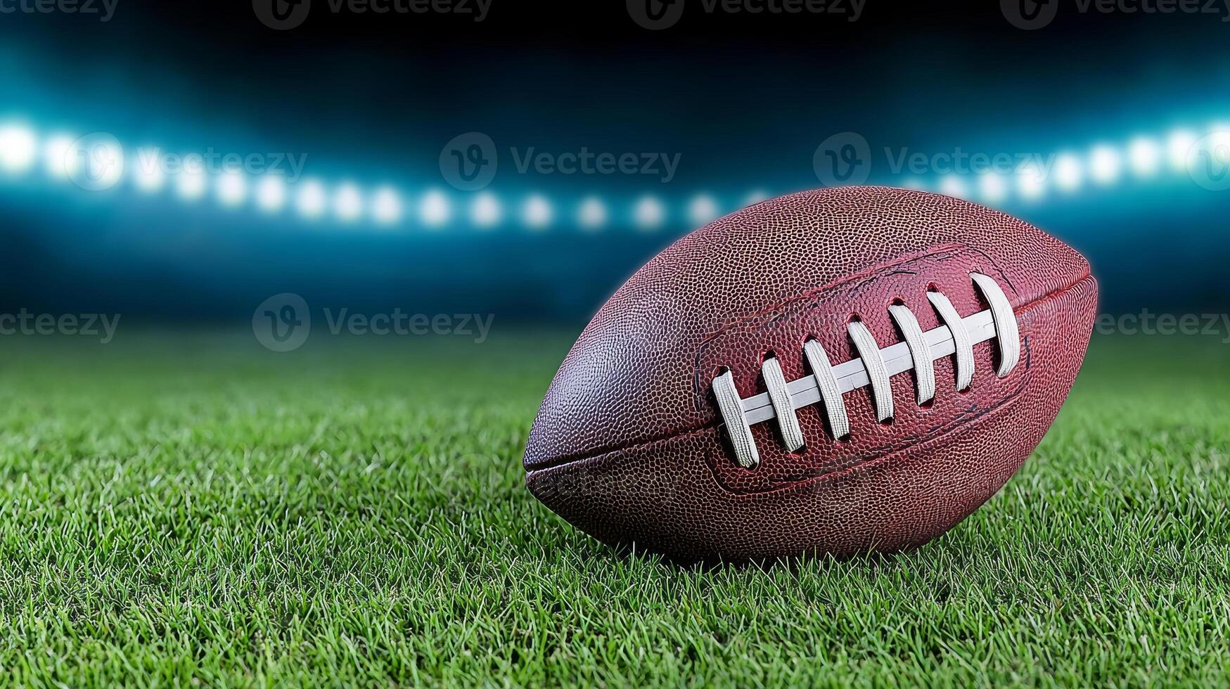 A close-up of a football resting on green grass under stadium lights, showcasing texture and detail in a sports setting. photo
