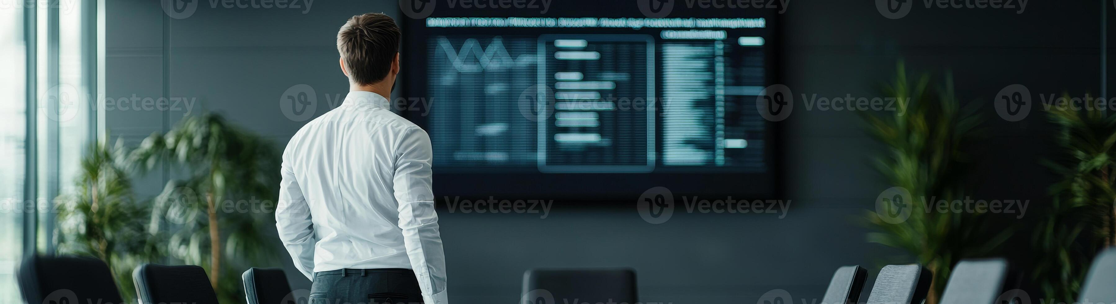 Management problem solving supervision concept. A professional looking man observes data analytics displayed on a large screen in a modern office setting. photo