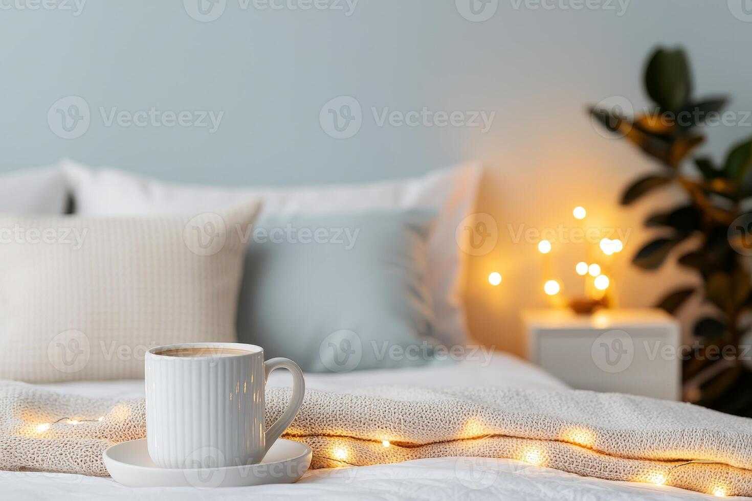 Self-care routines for Wellness concept. Cozy bedroom scene featuring a cup of coffee, soft pillows, and warm fairy lights, creating a serene and inviting atmosphere. photo