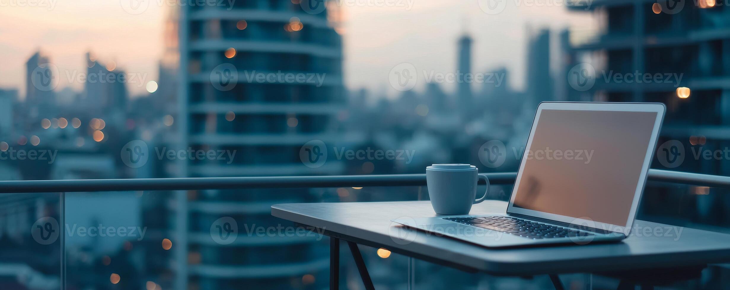 Business entrepreneurship with remote work concept. Workspace on a balcony with a laptop and coffee, overlooking a city skyline at dusk. photo