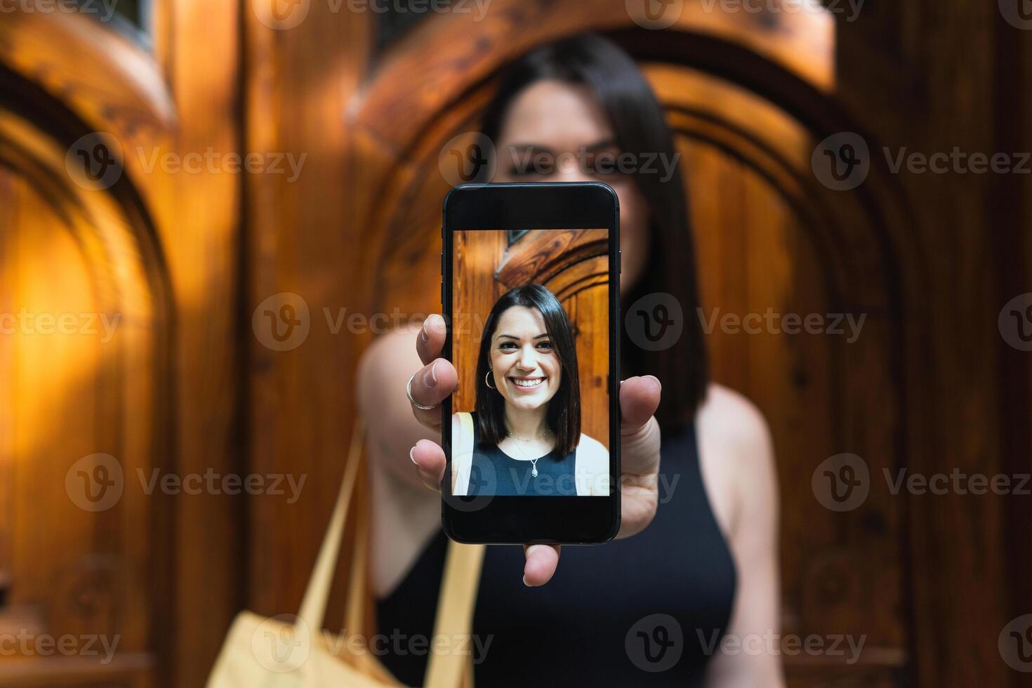 A woman holding up a smart phone with a photo of herself on it