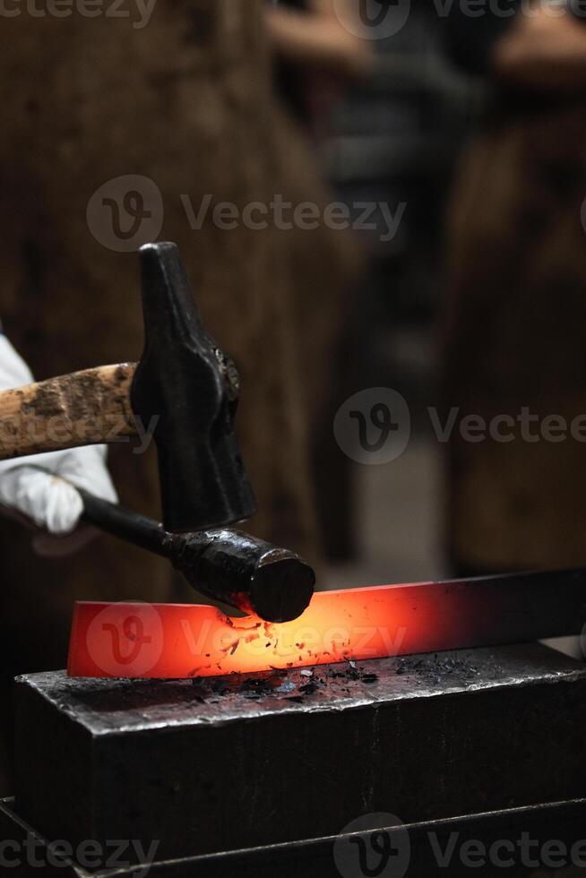 A blacksmith is working on a piece of metal photo
