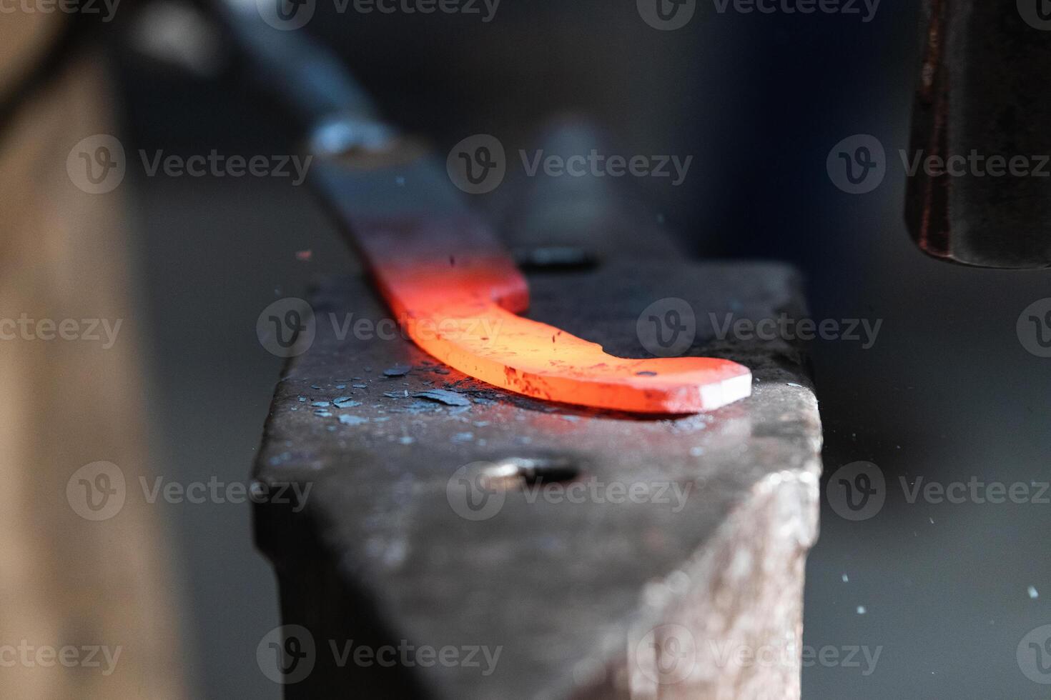 A blacksmith is using a hammer to make a piece of metal photo