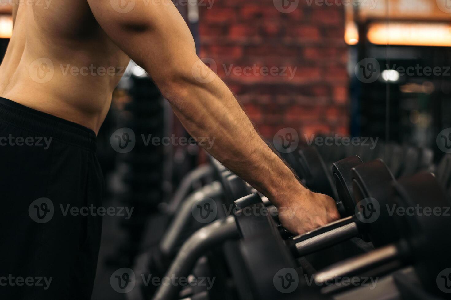 A man is holding a dumbbell in a gym photo