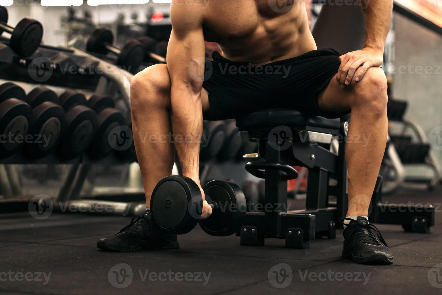 A man is sitting on a bench in a gym photo