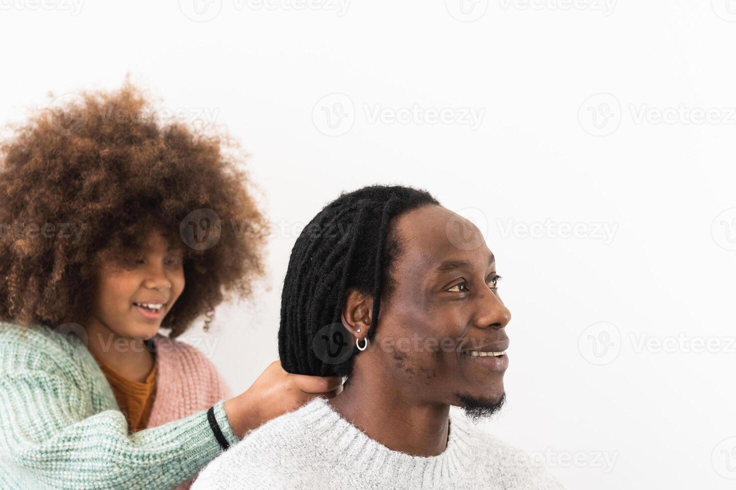 A man and a young girl are smiling while getting their hair done photo