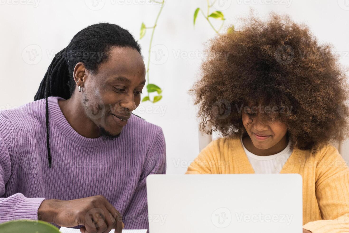 A man and a young girl are looking at a laptop photo
