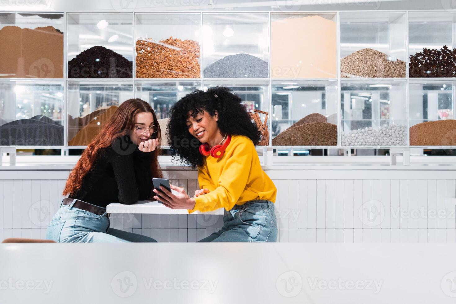 Two women sitting at a table looking at a tablet photo