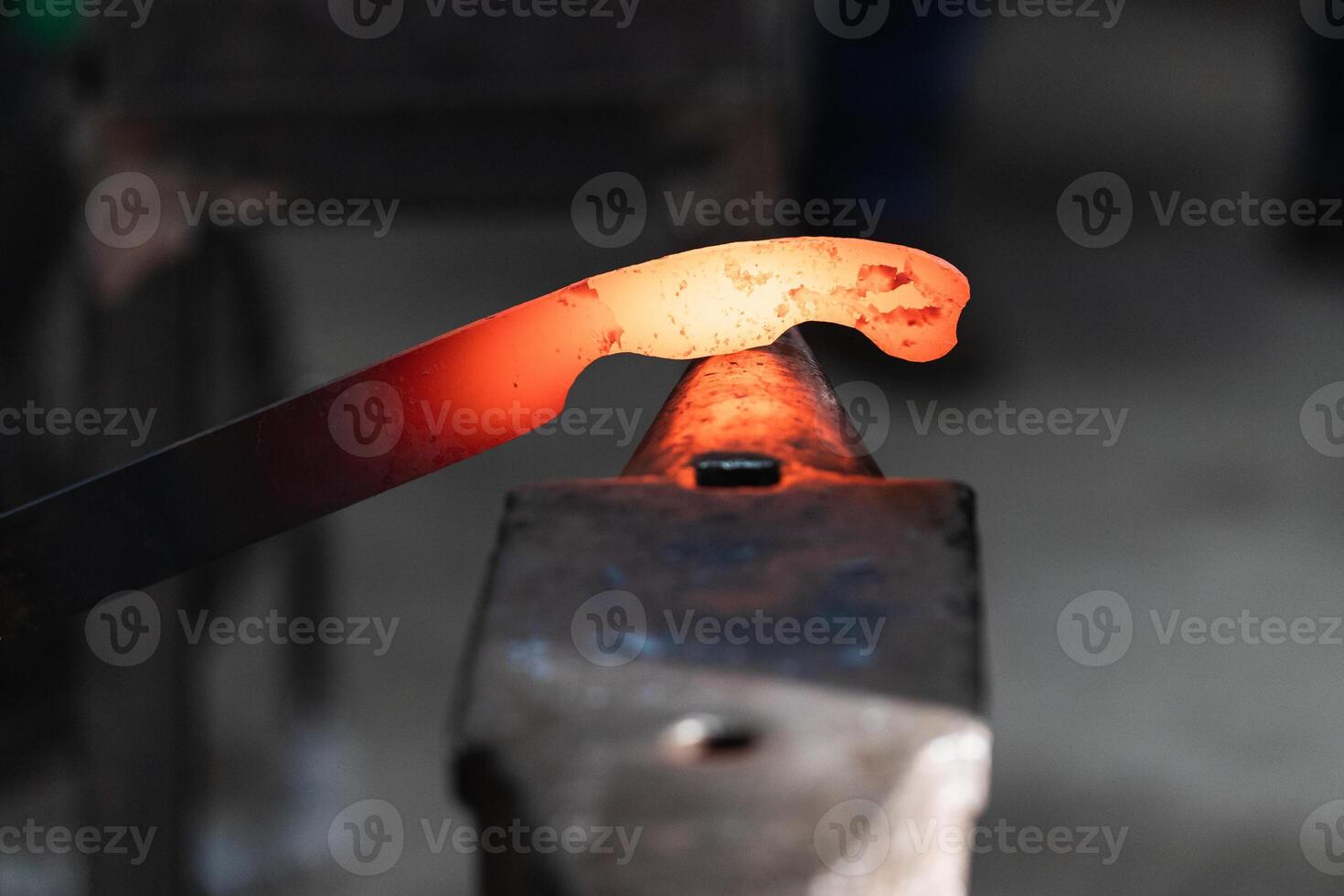 A person is using a hammer to make a piece of metal photo