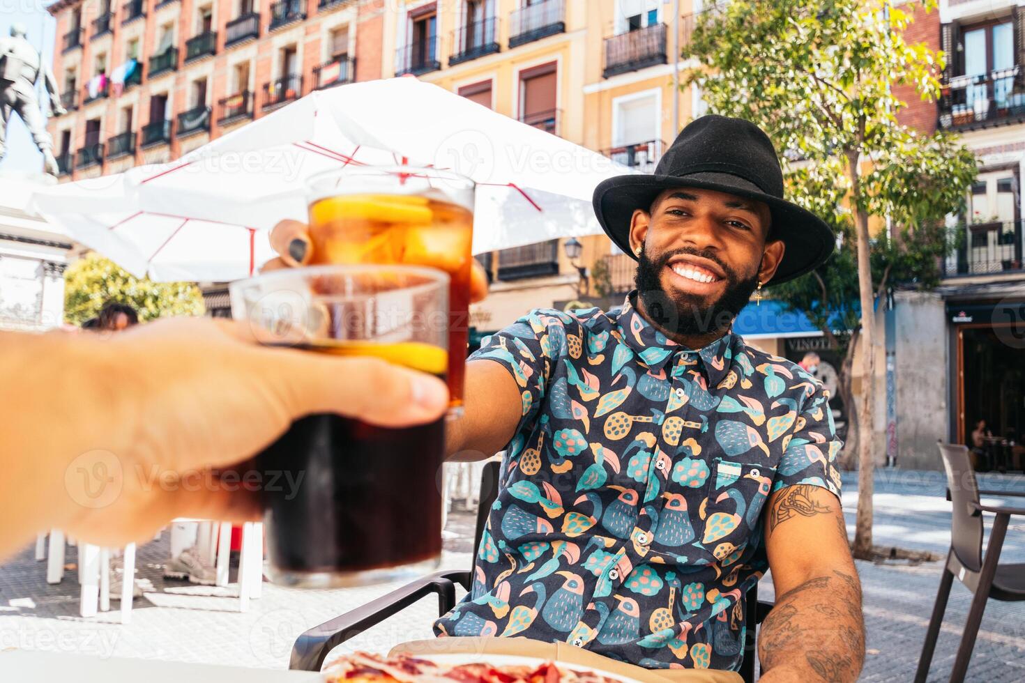 A man with a hat and a drink in front of a pizza photo