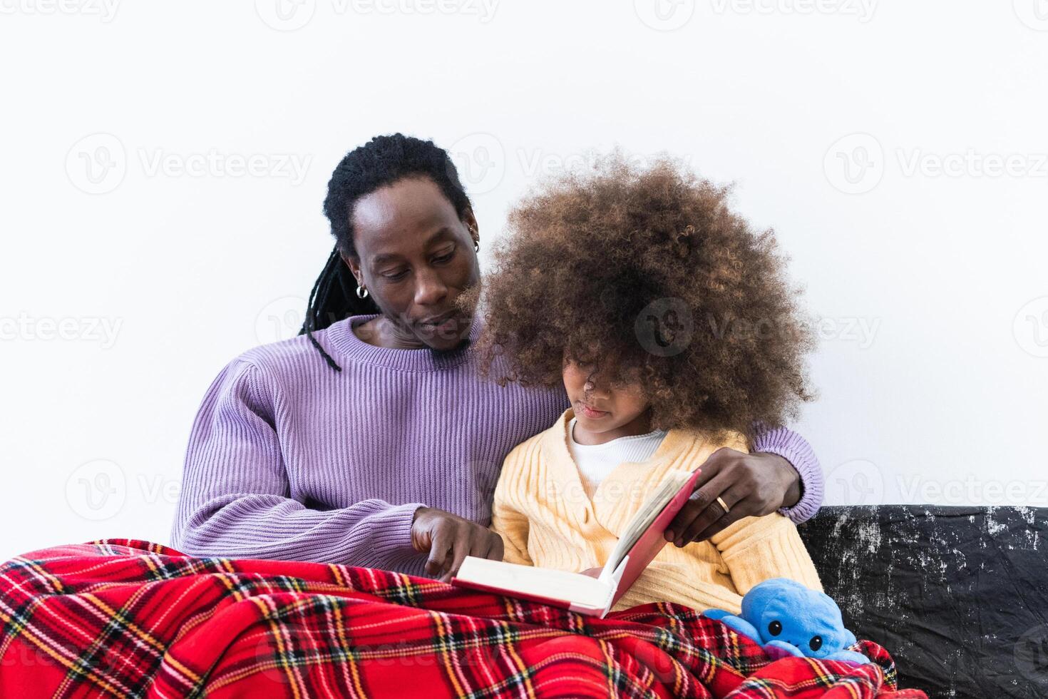 A man and a little girl sitting on a couch reading a book photo