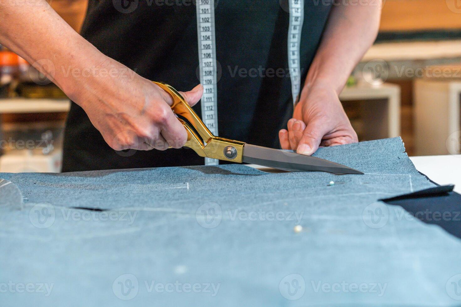 A person cutting fabric with a pair of scissors. Dressmaker in action photo