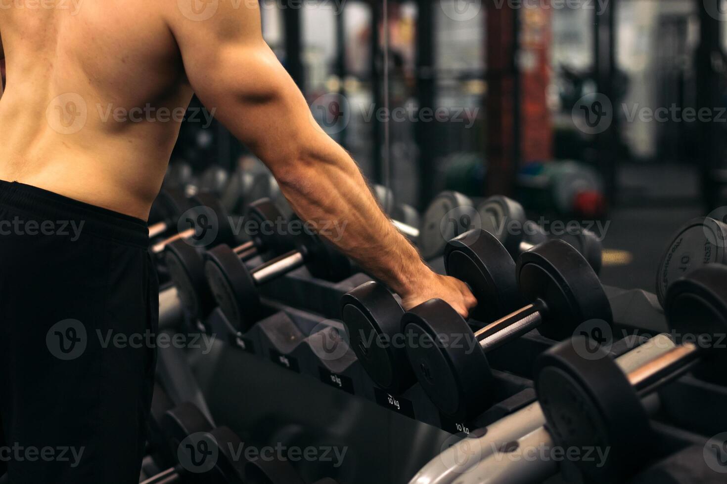 A man is standing in front of a gym with dumbbells photo