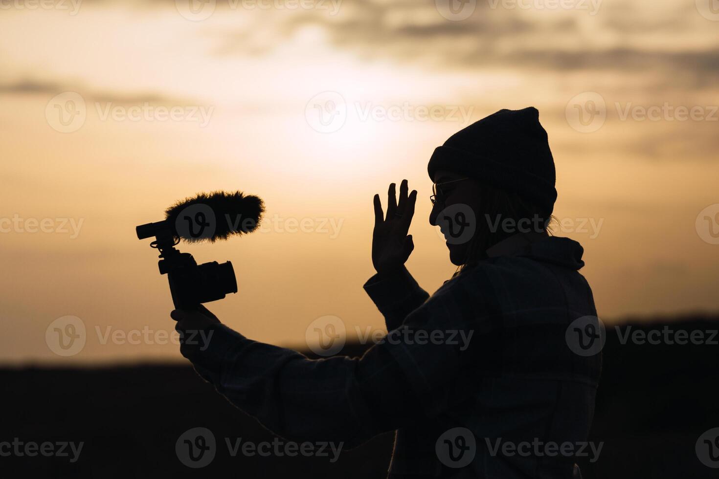Anonymous happy lady recording vlog on camera under sundown sky photo
