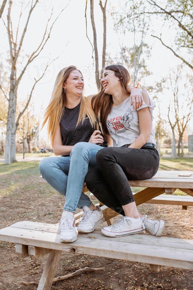 Girl friends hugging and laughing in park photo