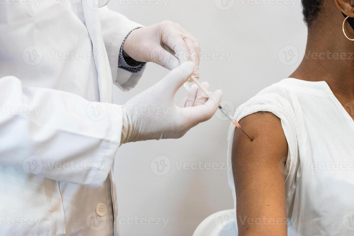 Doctor making injection for black woman patient photo
