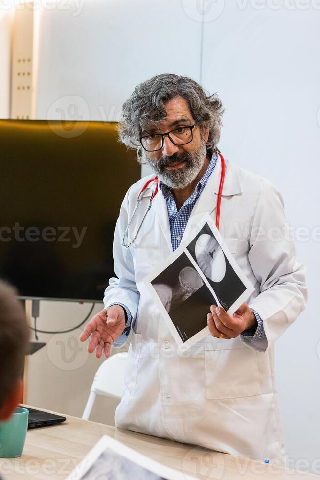 Senior doctor discussing x ray with colleagues in hospital photo