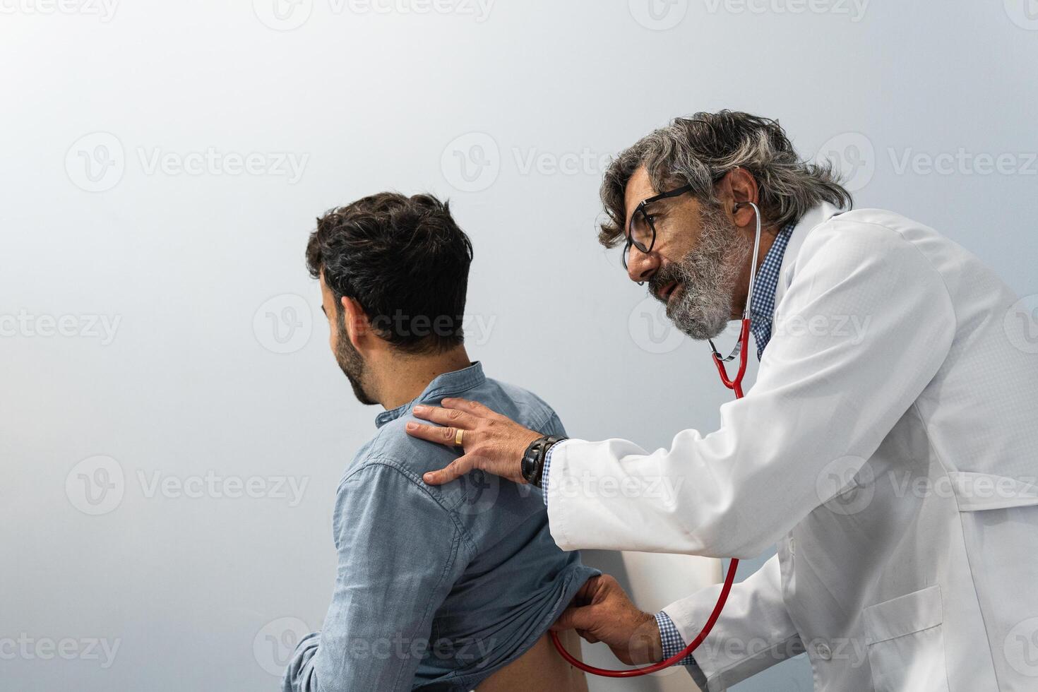 Male doctor using stethoscope and examining patient photo