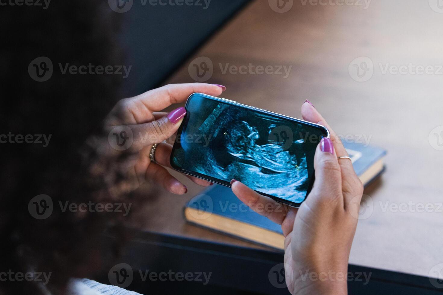 Ethnic woman watching baby ultrasound picture on smartphone photo