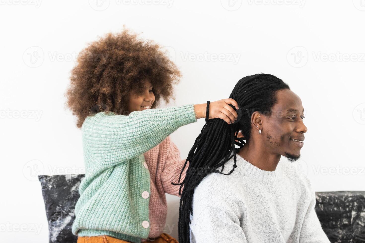 Amazed girl making hairdo on dreadlocks of father photo