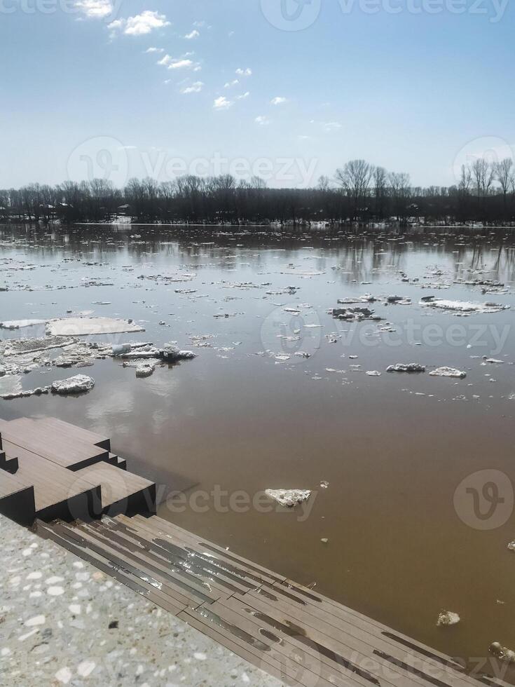 A serene flooded area is covered with river ice and debris, under clear blue skies. Natures beauty blends with environmental changes, creating a tranquil scene photo
