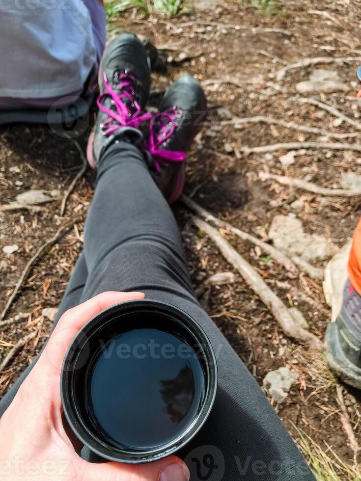 In a peaceful setting, a person relaxes on soft grass, enjoying a warm cup of aromatic coffee and savoring each sip while admiring the stunning beauty of nature around them photo