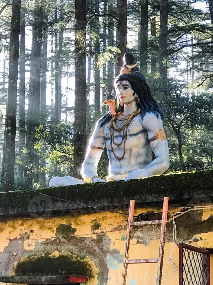 A grand statue of Lord Shiva stands tall in the serene Himachal Pradesh forest, offering a stunning scene for visitors and worshippers to admire and find solace photo