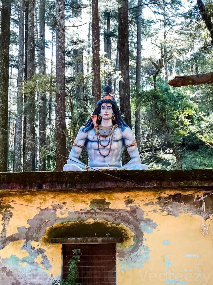 The stunning and majestic statue of Lord Shiva stands tall and proud, beautifully surrounded by a lush green forest that enhances its grandeur and serenity, inviting exploration photo