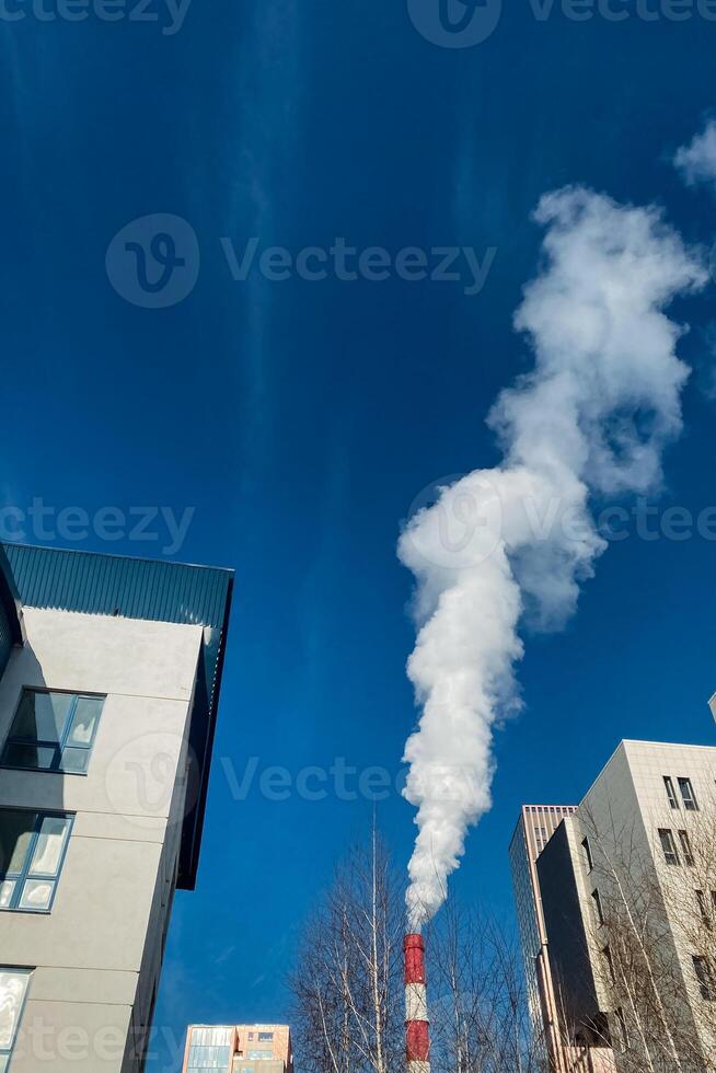 A distinct plume of smoke is billowing out of the chimney placed strategically between two neighboring buildings situated in an urban area, indicating possible activity indoors or pollution photo