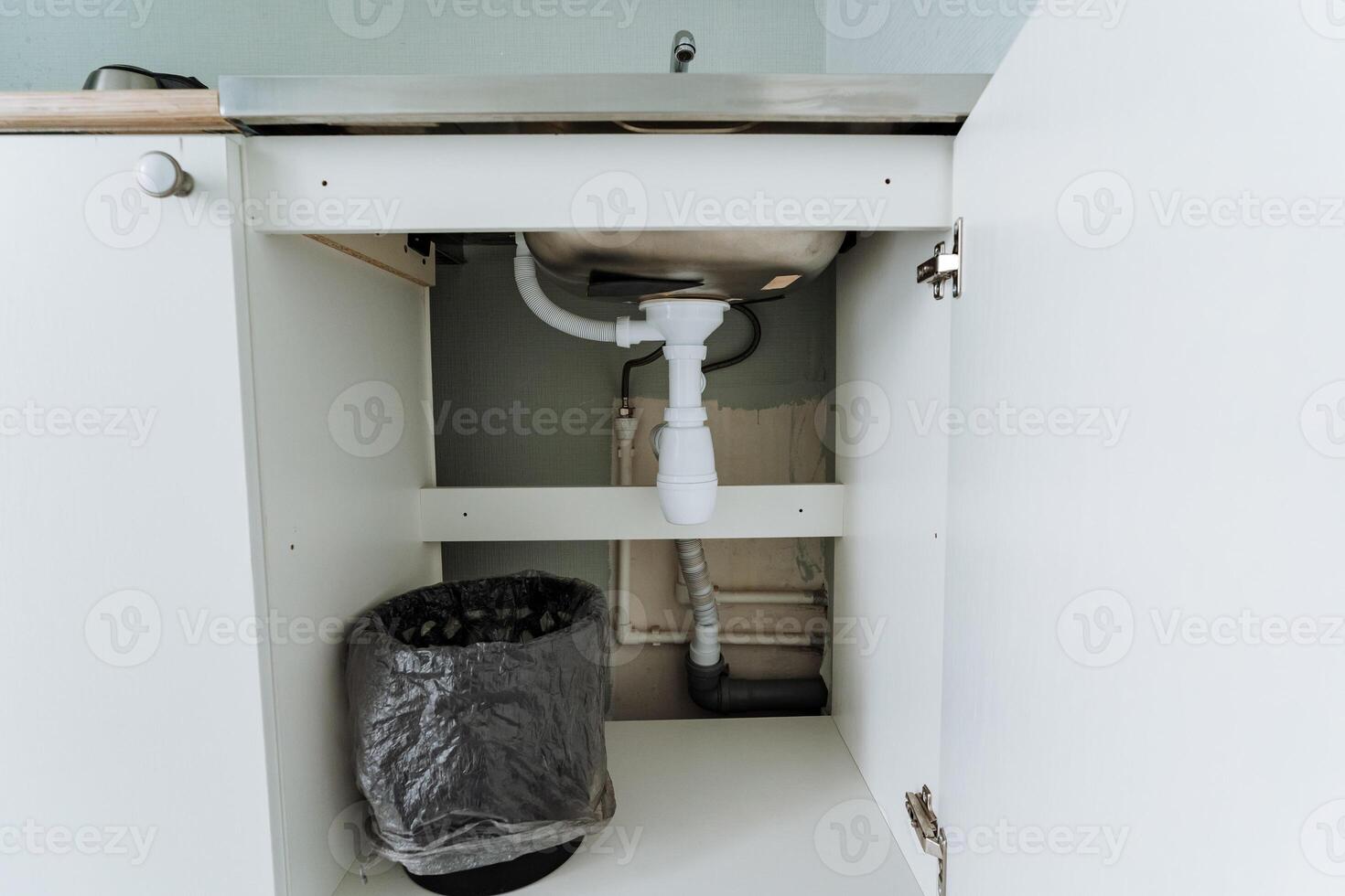 Located conveniently beneath the sink inside the cabinet, there is a trash can that serves the purpose of keeping the area organized and promoting cleanliness throughout the space photo
