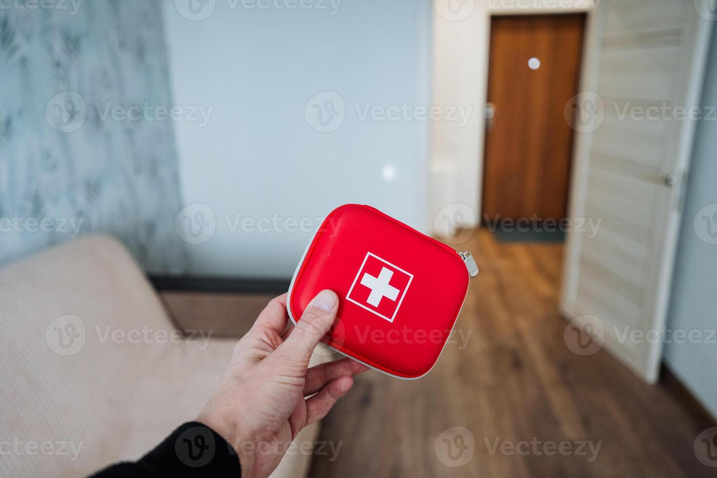 A person is firmly and confidently holding a bright red first aid kit, which is absolutely essential for providing crucial medical assistance during emergencies when it is needed the most photo
