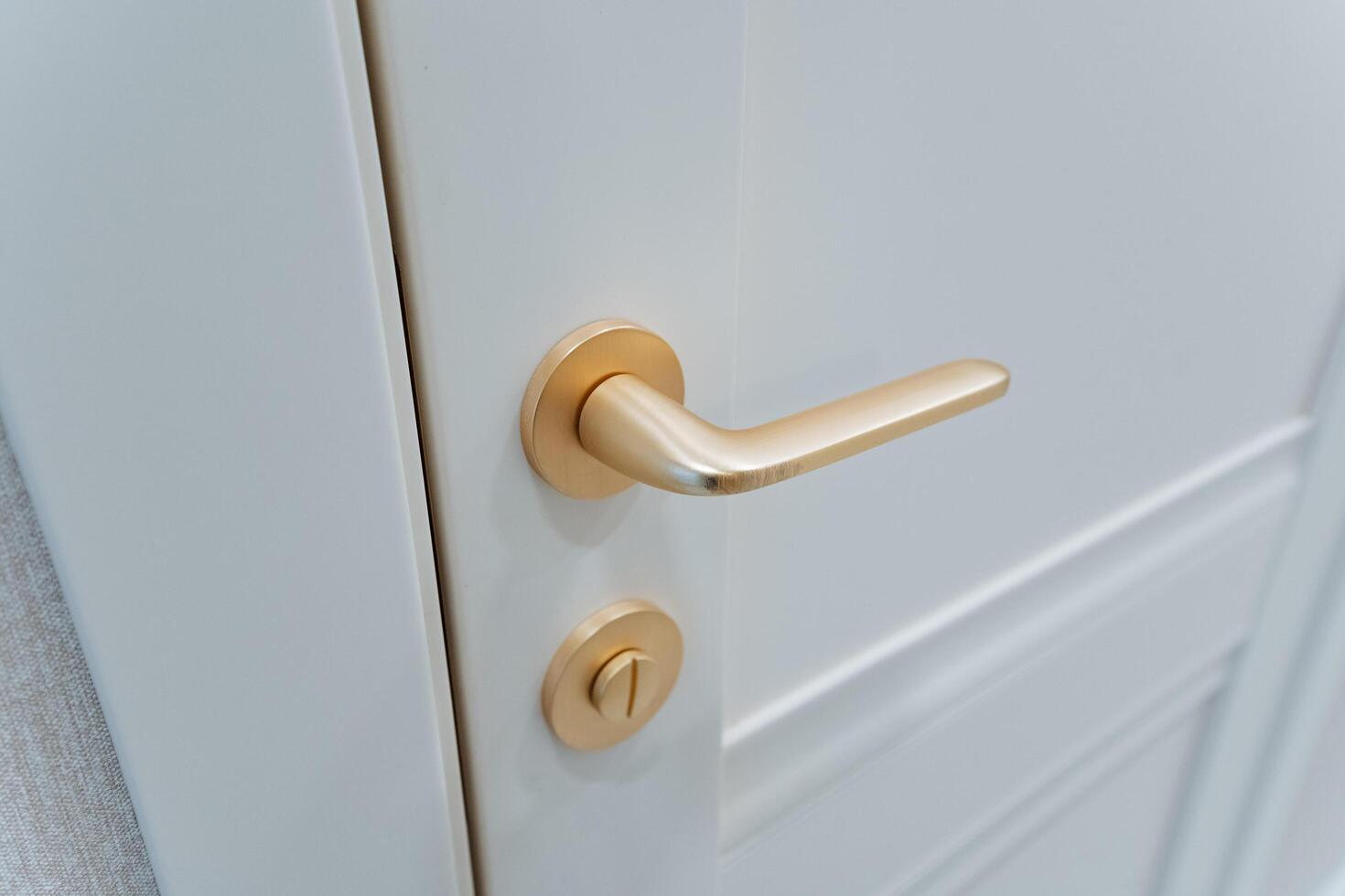 Here is an extensive and detailed description of a pristine white door, which features an elegant gold door handle that beautifully complements its overall aesthetic and design photo