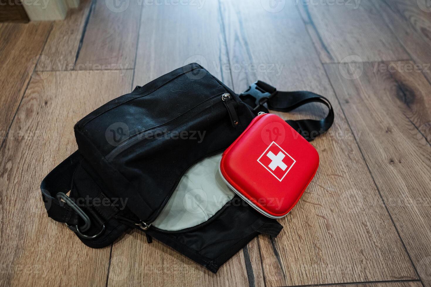 A first aid kit is conveniently located next to a black bag, which may serve as either luggage or a personal item, ensuring quick and easy access during emergencies when needed photo