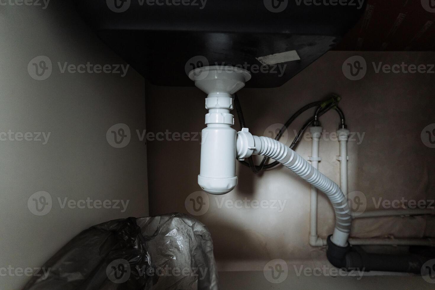In a cramped, dimly lit room, there is a sink that sits with a drain pipe directly below it, which is essential for effective wastewater disposal within the plumbing system photo
