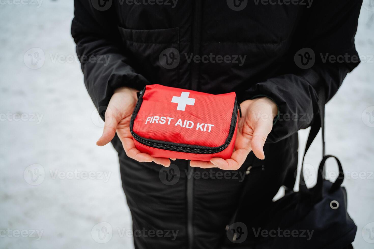 A person stands confidently, holding a vibrant red first aid kit that indicates preparedness, ready to assist in emergencies and ensure the utmost safety for anyone in urgent need photo