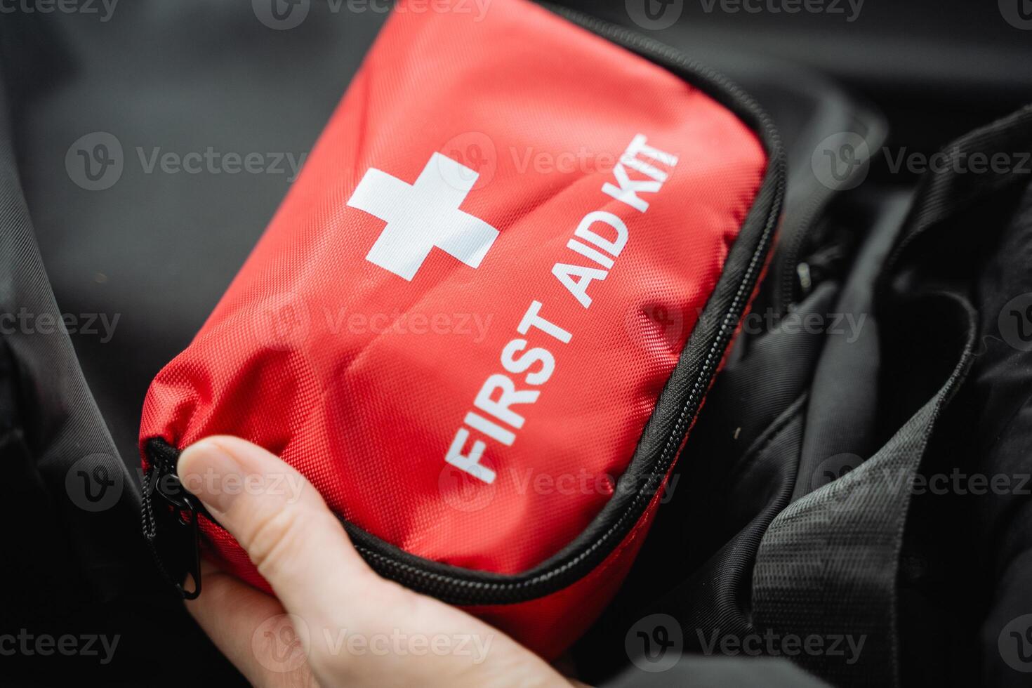 A person confidently holds a bright red first aid kit in their hands, fully prepared to assist anyone in need or to respond quickly and effectively to any emergency situation that may arise photo