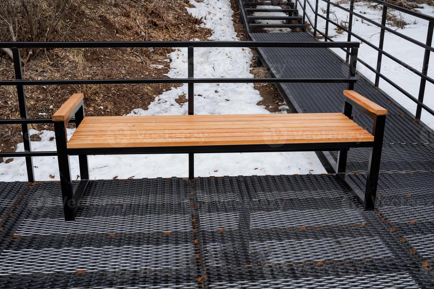 A robust and sturdy wooden bench is carefully placed on a durable metal platform adjacent to the stairs, enhancing the inviting and functional experience of the outdoor seating area photo