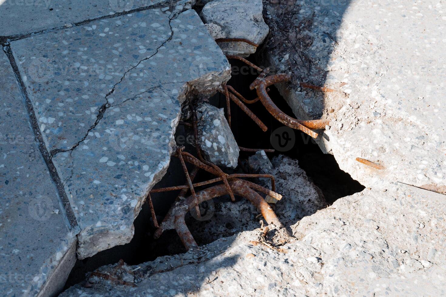 A cracked concrete floor that has a noticeable hole indicates ongoing wear and tear over time, which suggests a significant and prolonged history of environmental impact and distress photo