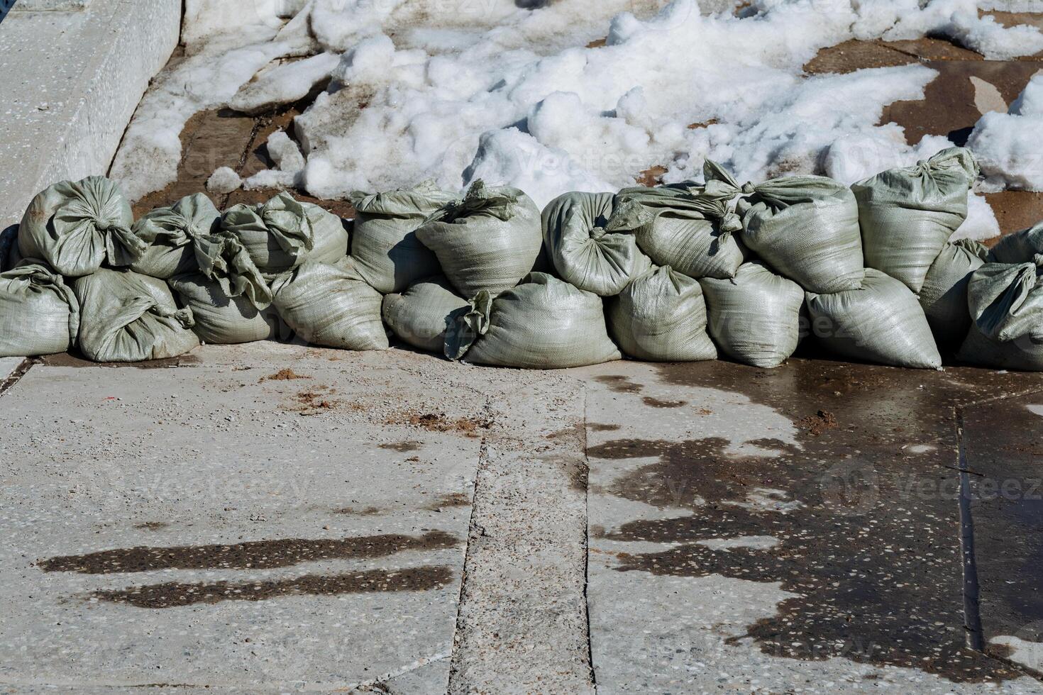 A sizable pile of sandbags is currently positioned on the side of a road, presumably for purposes related to construction or safety measures during adverse weather conditions photo