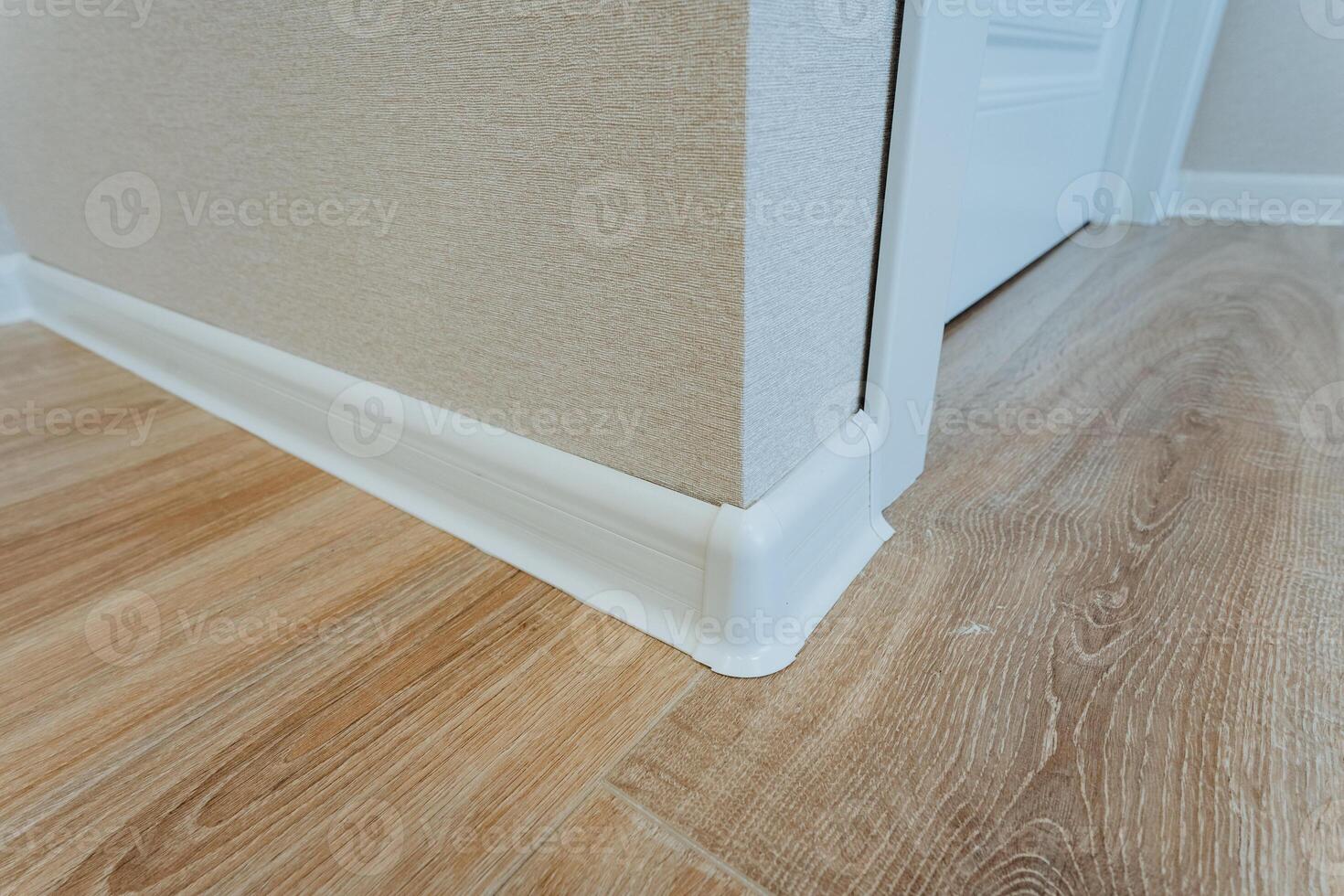 In a cozy corner of a room, there is a beautifully finished wooden floor that contrasts elegantly with the bright white trim, creating a welcoming and stylish atmosphere photo