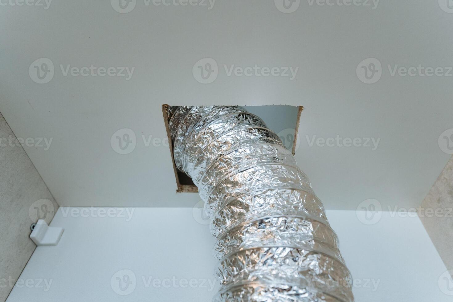 A shiny silver duct protrudes conspicuously from the ceiling, which indicates the presence of a ventilation or piping system that has been installed in the space above our heads photo