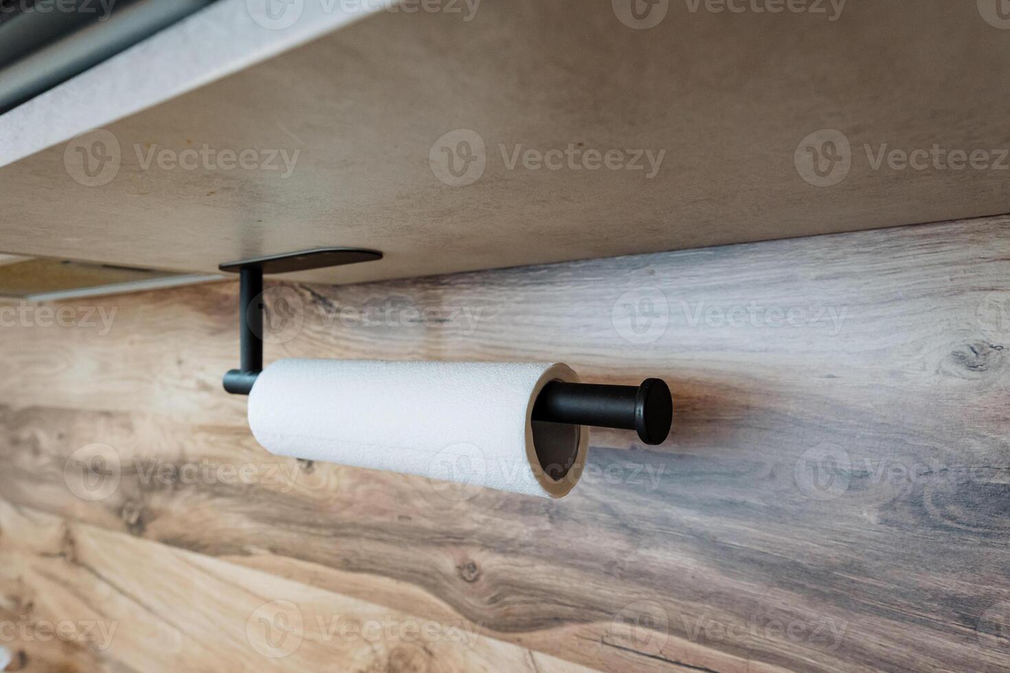 A roll of paper towels is hanging from a paper towel holder on a wooden wall photo