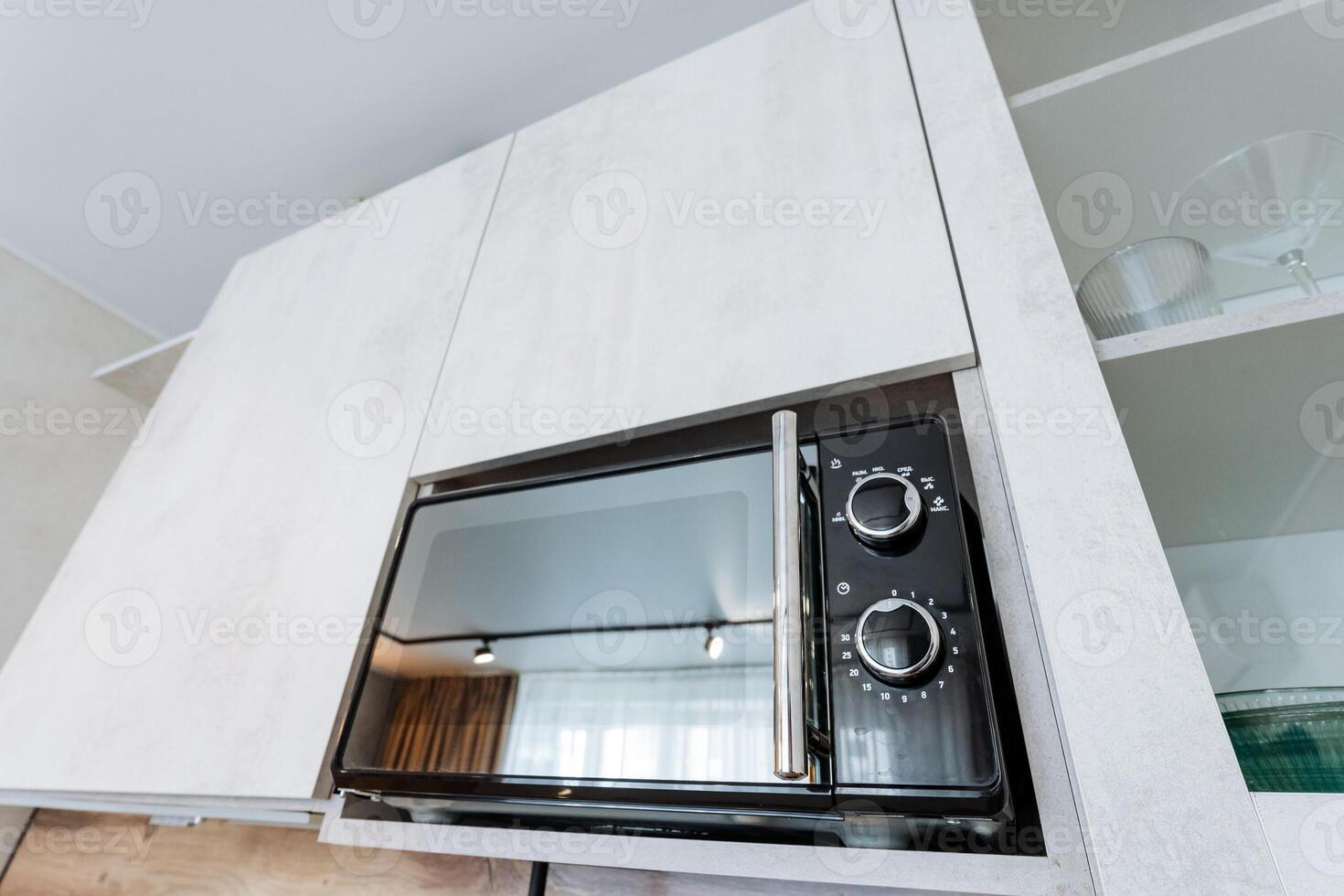 A microwave oven is cleverly and smartly installed within a stylish cabinet located in the center of a contemporary kitchen, significantly enhancing both its functionality and visual appeal photo