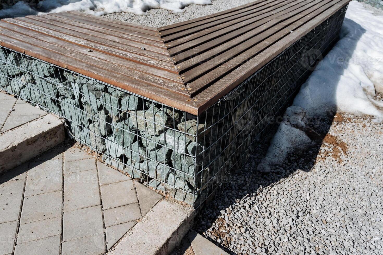 A sturdy and durable wooden bench placed next to a weathered stone wall significantly enhances the outdoor aesthetic and creates a delightful spot for relaxation amid beautiful surroundings photo