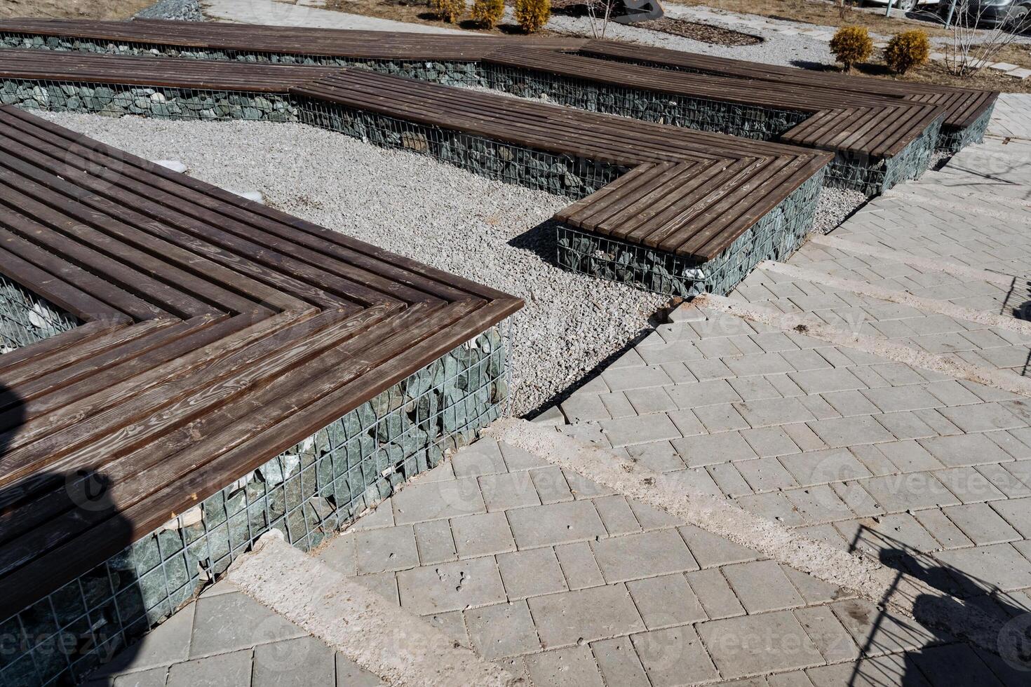 There is a picturesque row of beautifully crafted wooden benches that are placed meticulously on top of a wellconstructed brick walkway, creating a charming outdoor seating area photo