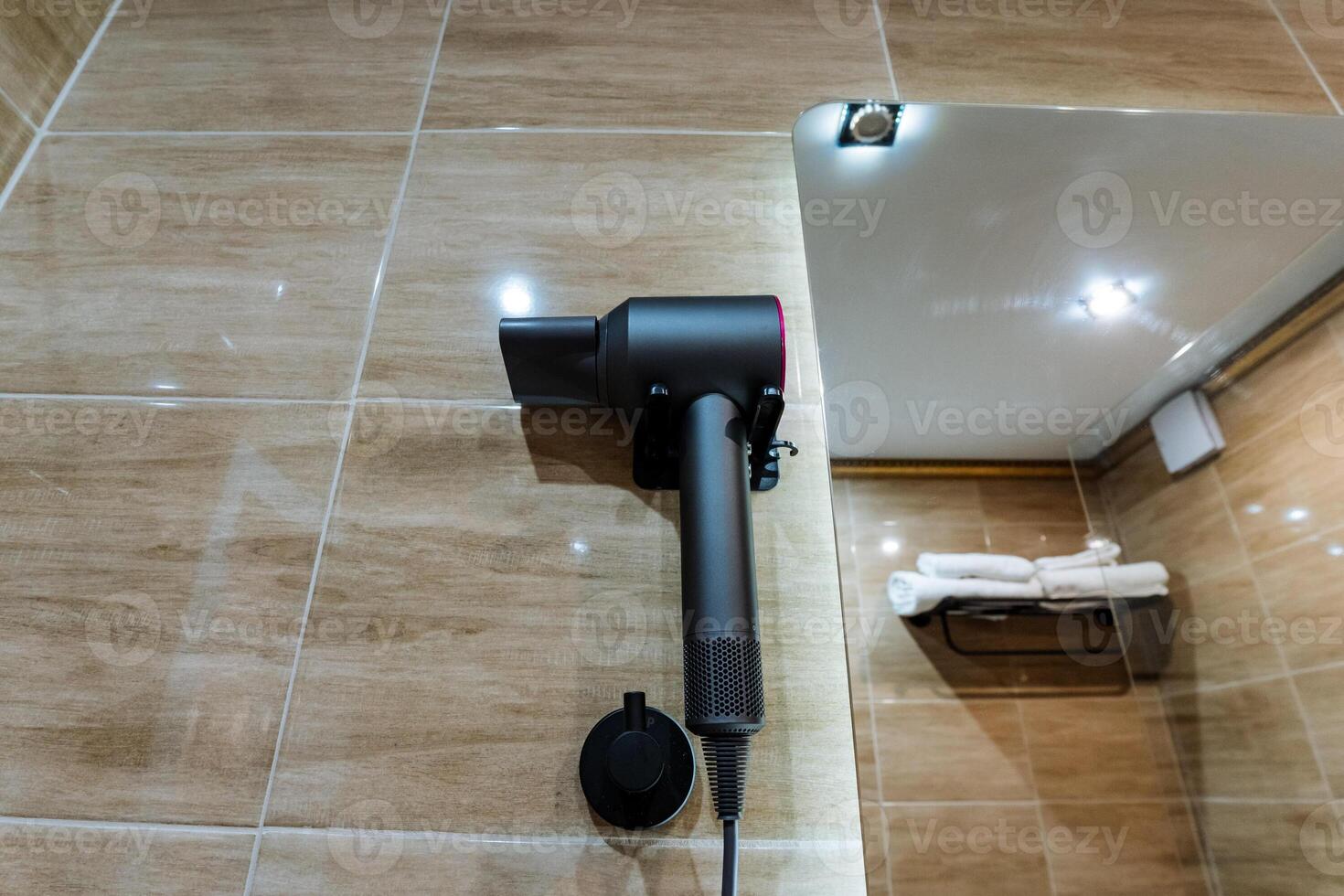 A hair dryer that is securely mounted on the bathroom wall becomes conveniently accessible for anyone who wishes to use it right after enjoying a refreshing shower or a soothing bath photo