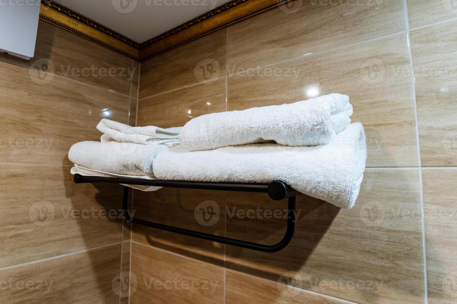 A neatly arranged stack of crisp, white towels is hanging on a polished towel rack in a beautifully designed bathroom, creating a sense of cleanliness and comfort for users photo