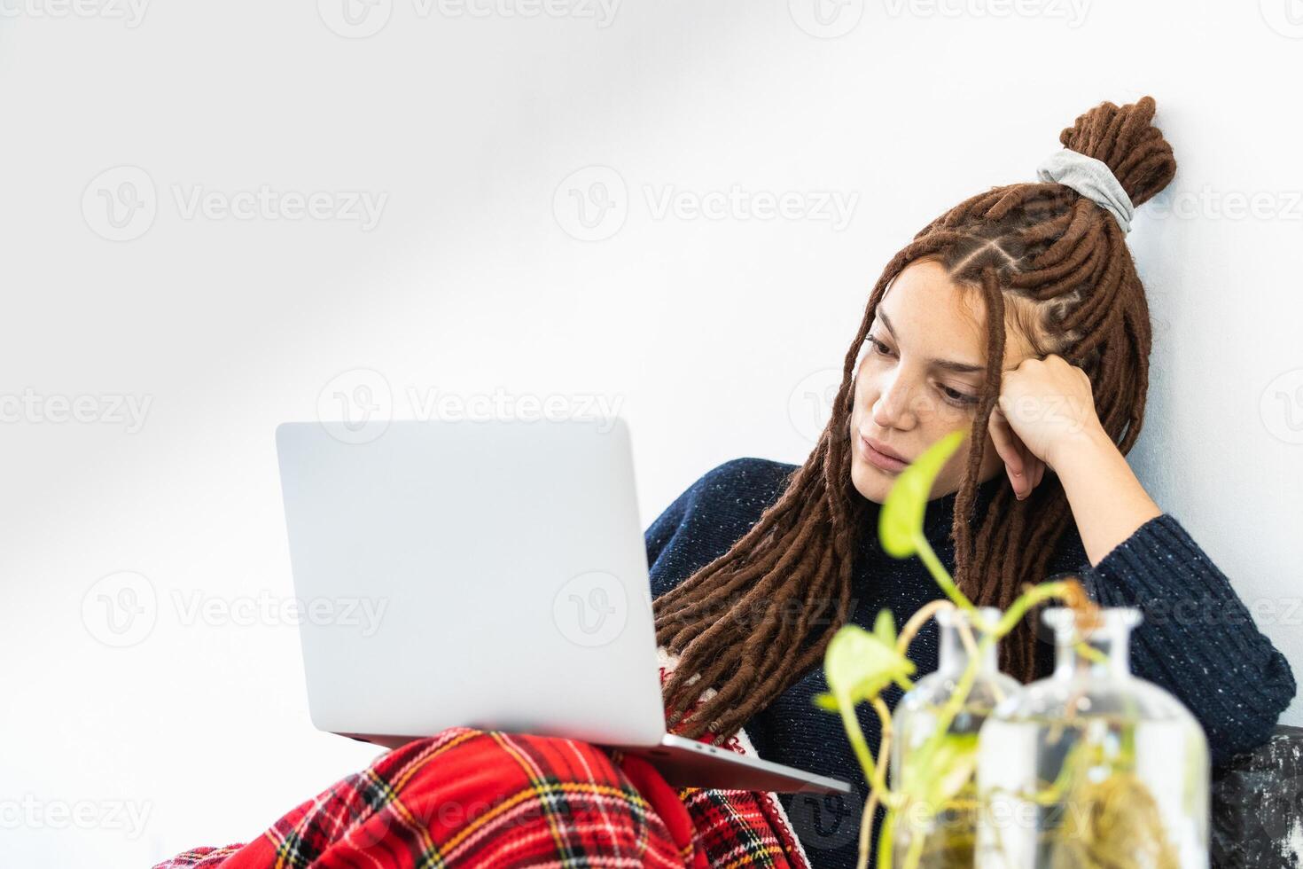Woman with dreadlocks working with a laptop at home photo