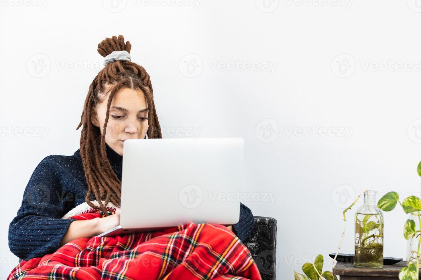 Woman with dreadlocks working with a laptop at home photo
