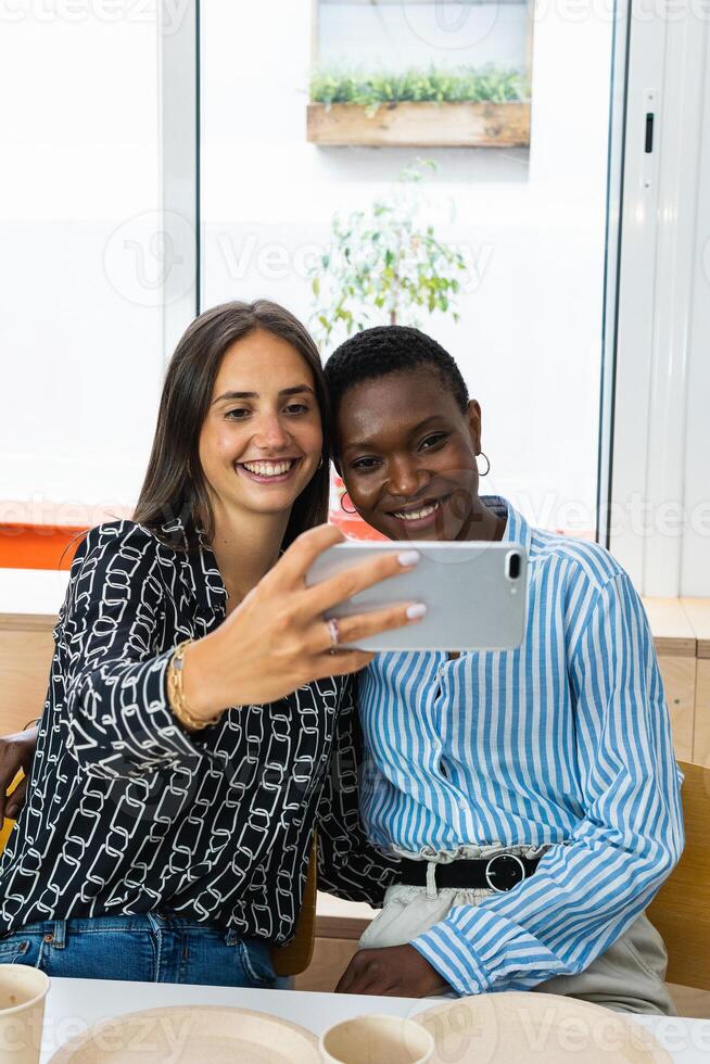 Smiling multiethnic coworkers taking selfie during break in office photo